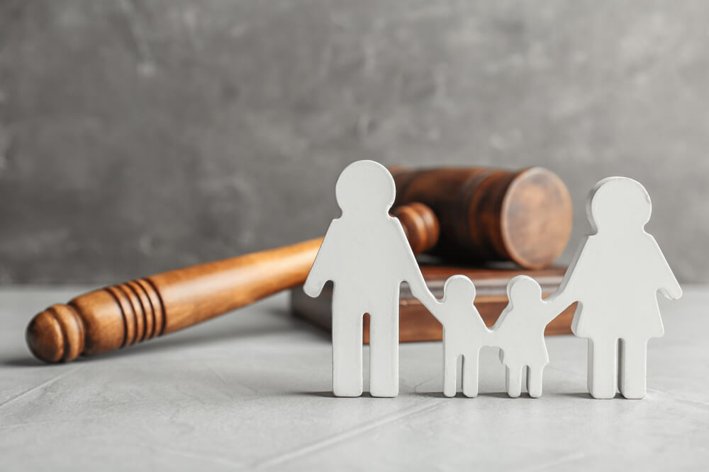A white block cutout of a family stands in front of a gavel, symbolizing child support.